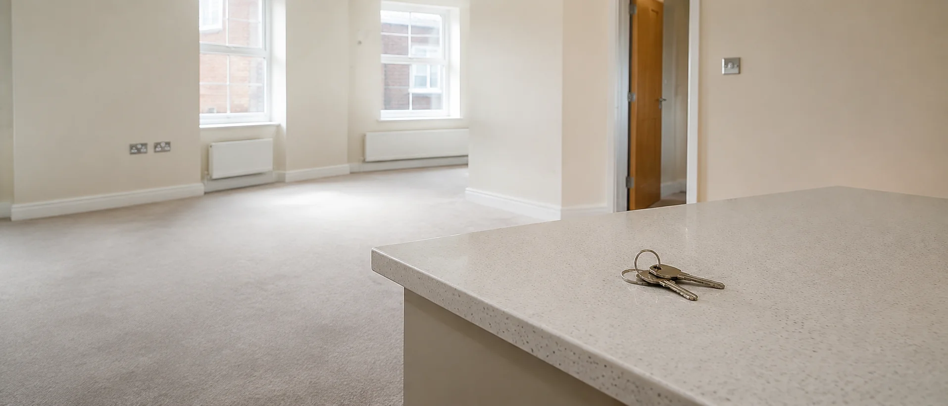 Empty, immaculate rental living room, keys on a clean worktop in the foreground, bright and neutral